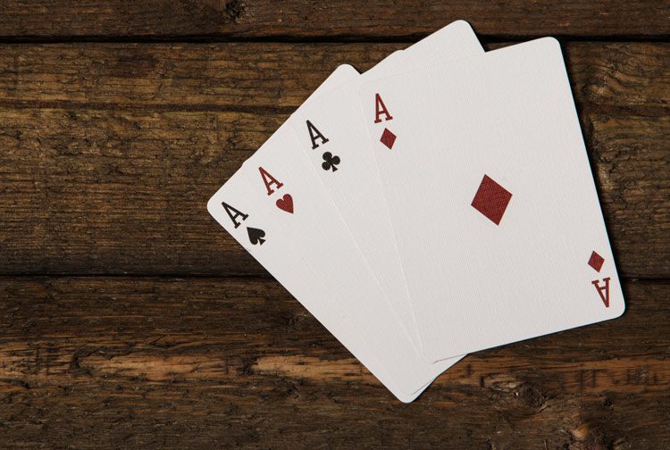 four aces spread on a dark wooden table - ACEs